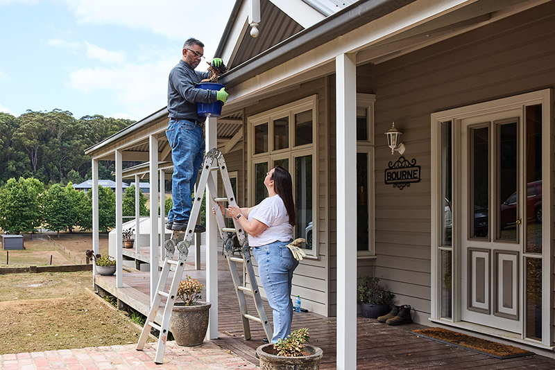 Couple clearing leaves from gutter